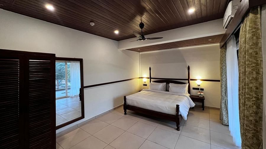 Grand Suite room with a comfortable bed, wooden furniture, and large window at Mastiff Grand La Villae Resort, Lonavala